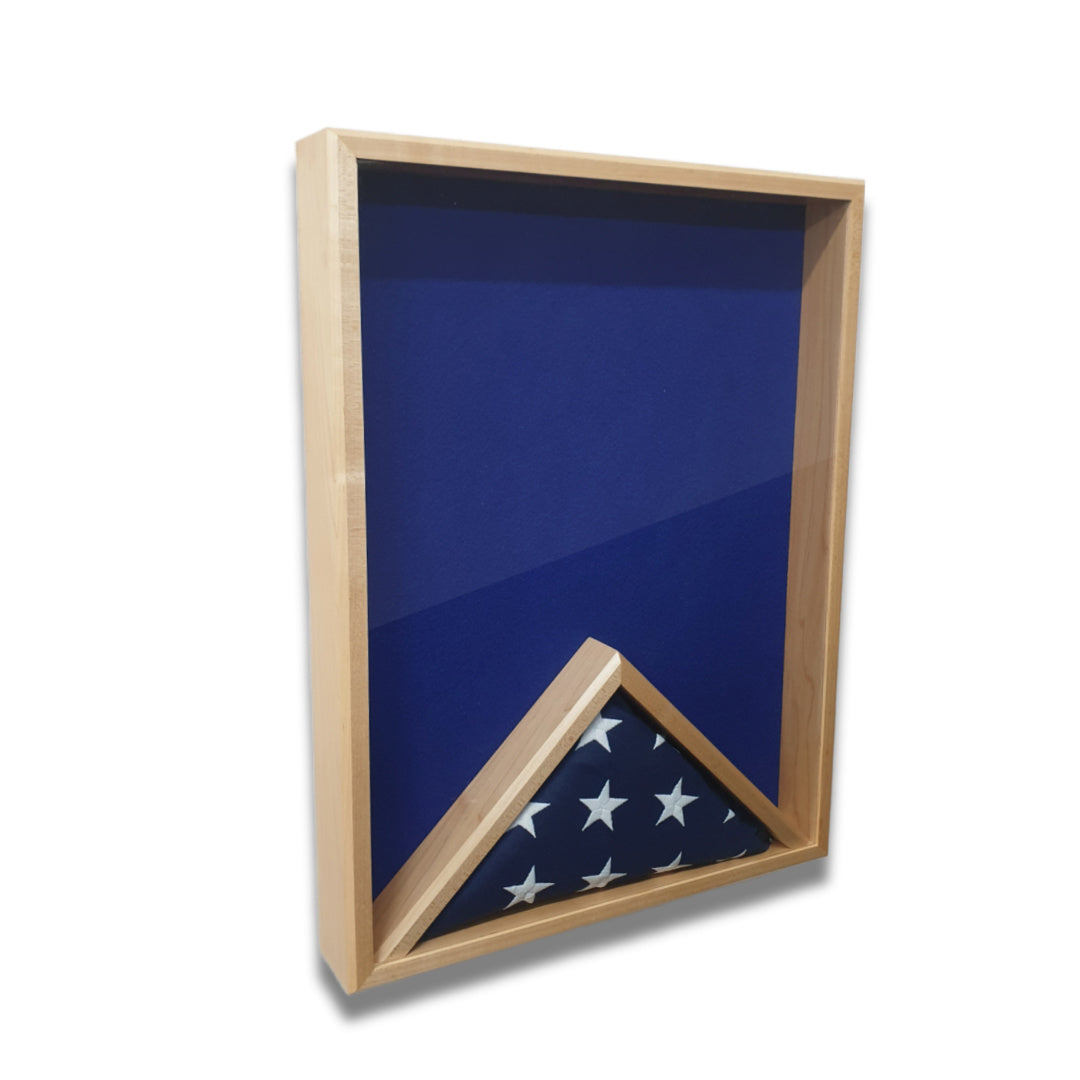 Maple 18x24 vertical shadow box shown at a slight left angle with blue felt backing and a folded American flag in the display area
