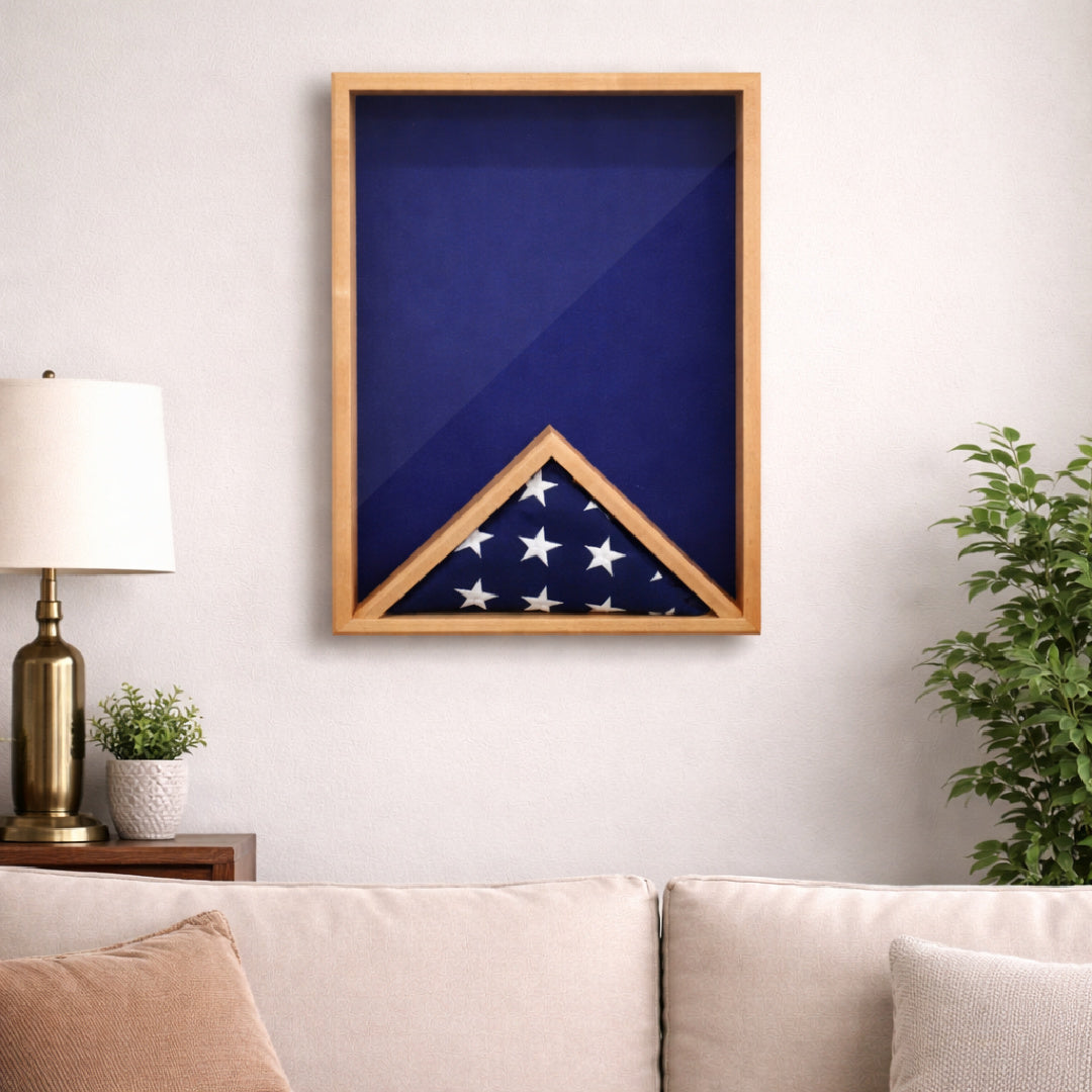 Maple 18x24 vertical shadow box hanging on a wall in a home setting, shown with a blue felt backing and a folded American flag inside