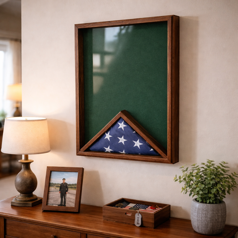 Walnut 18x24 vertical shadow box mounted on a wall in a home setting, featuring a folded American flag against a green felt backing with visible glass reflection