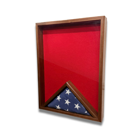 Walnut 18x24 vertical shadow box shown at a slight right angle with red felt interior and a folded American flag inside