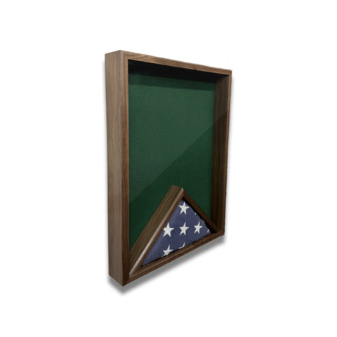 Walnut 18x24 vertical shadow box shown at a slight left angle with green felt backing and a folded American flag inside